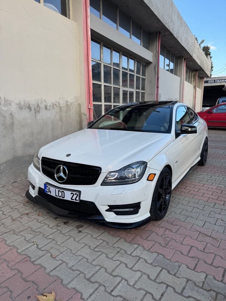 A white coupe photographed outdoors from the front three-quarter angle; an input-photo reference, not a generated result.